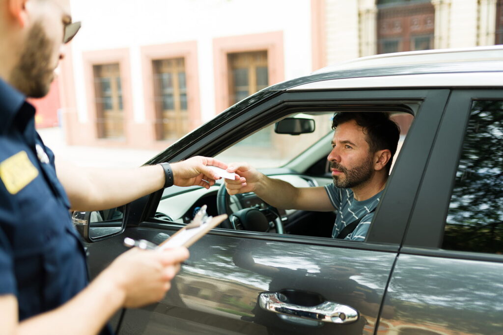 police officer handing moving violation ticket to male driver