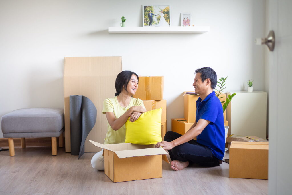 a couple sitting on an apartment floor with packed boxes