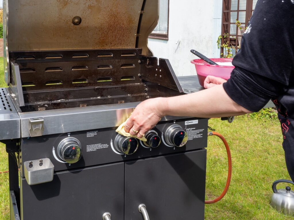 a homeowner cleaning an outdoor gas grill