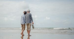 A senior couple walking hand-in-hand on a beach, symbolizing the security and peace of mind life insurance provides in retirement.