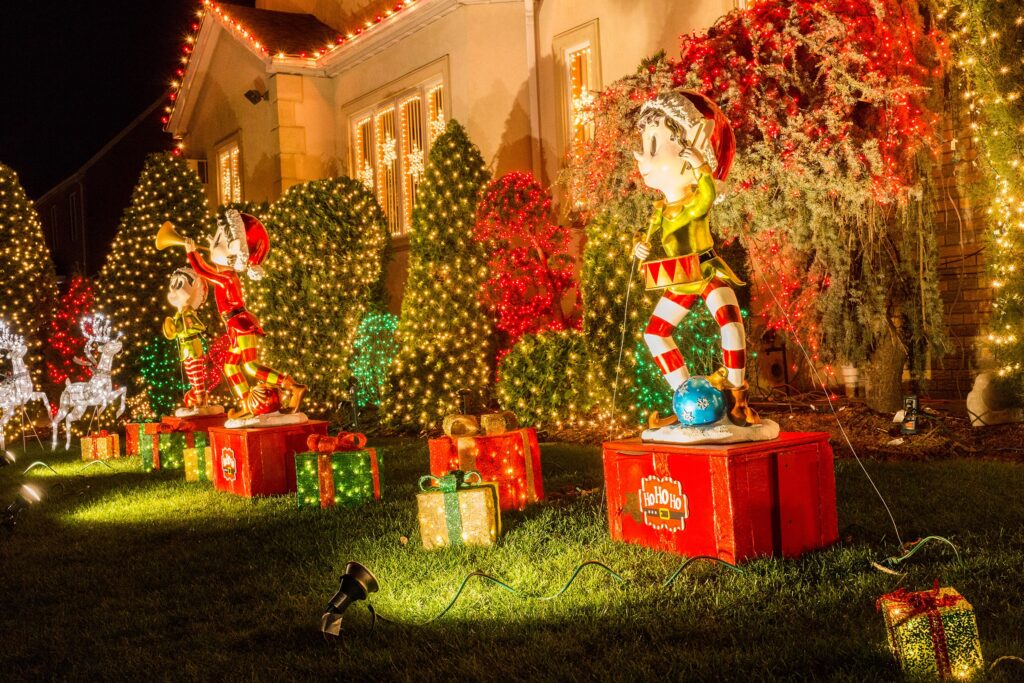 Close-up of a home with festive holiday lights and light-up lawn decorations, highlighting safety tips to prevent fire and liability risks.