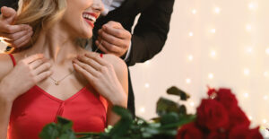 A joyful woman receiving a golden necklace and a bouquet of red roses as a Valentine's Day gift.