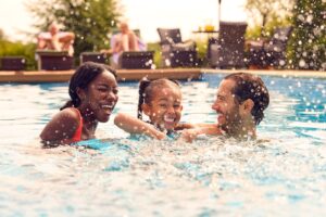 Family enjoying a backyard swimming pool on a sunny summer day, highlighting pool safety