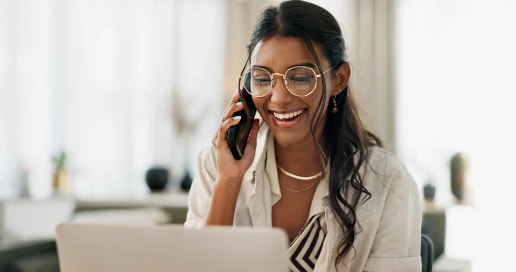 Woman reviewing insurance information on a laptop while speaking on the phone during an insurance coverage review.