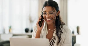 Woman reviewing insurance information on a laptop while speaking on the phone during an insurance coverage review.