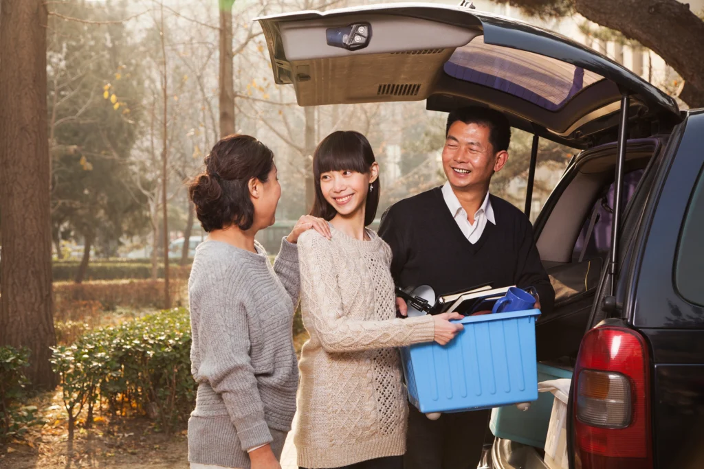Parents helping their college-age daughter unpack a van during college move-in day